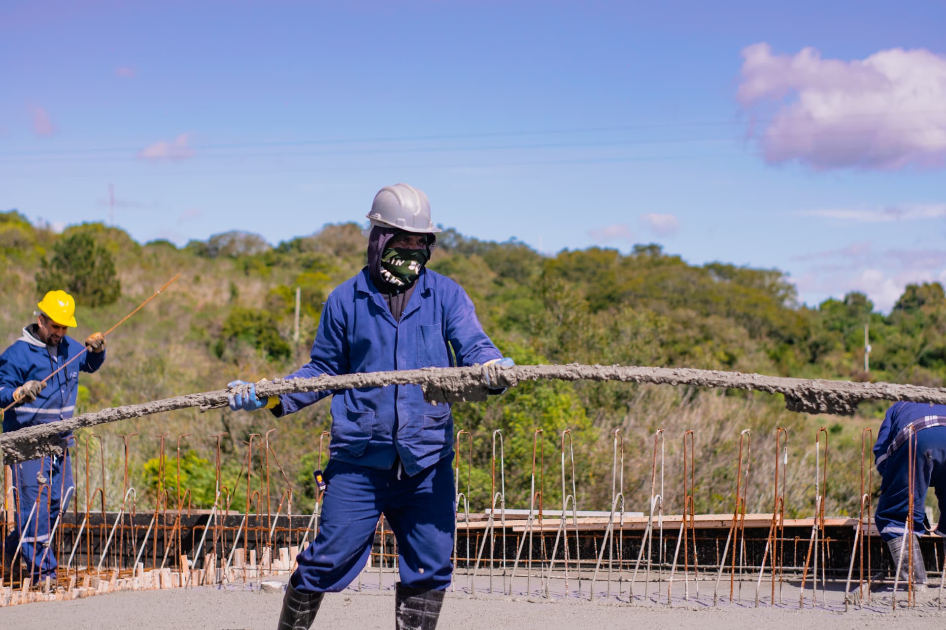 Operário espalhando concreto fresco sobre a laje da ponte