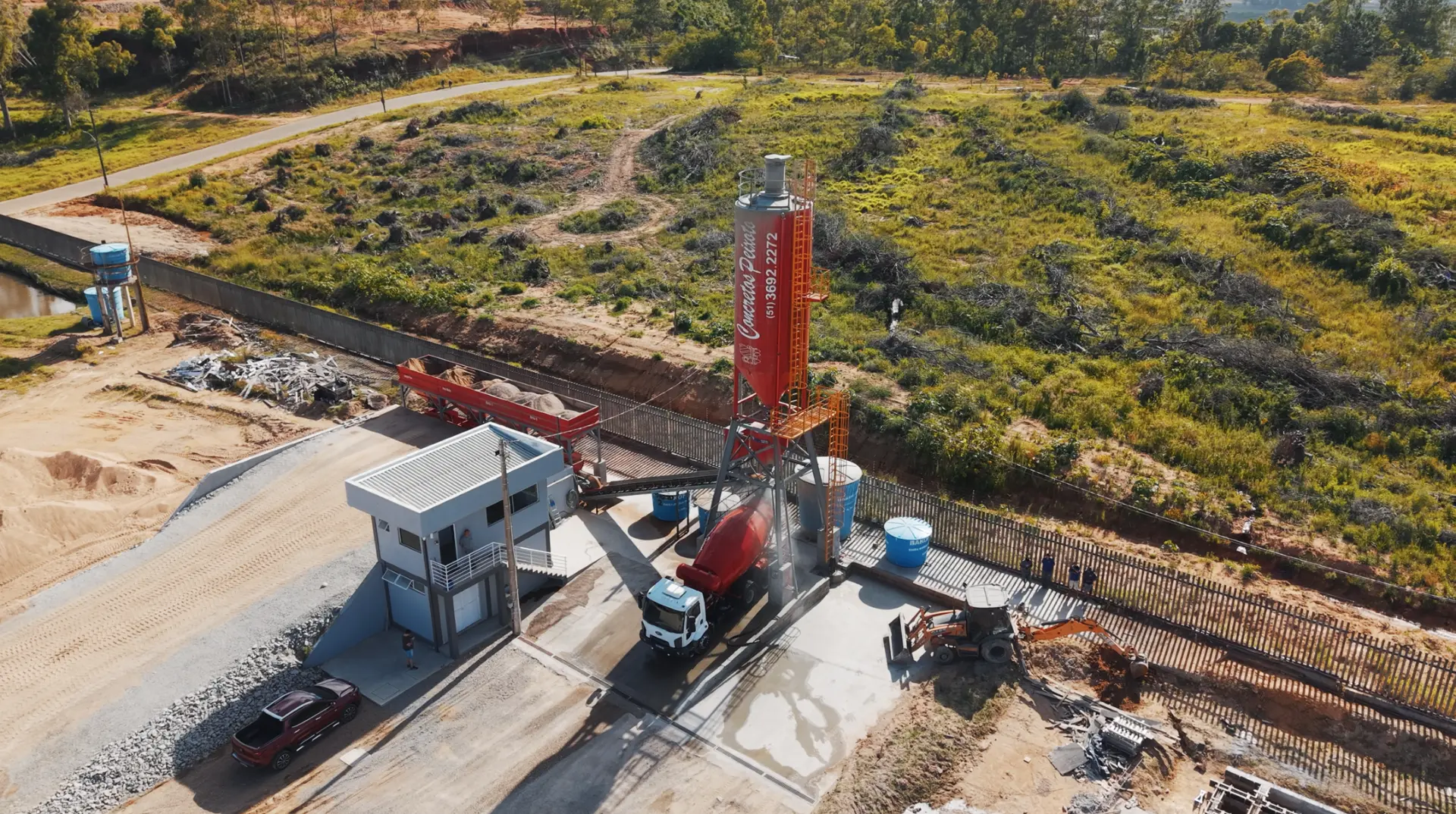 Silo vermelho da Concretos Peixoto e betoneira sendo carregada na central